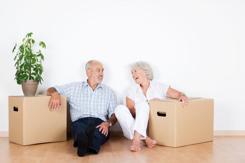 Senioren sitzen mit Umzugskartons in einer neuen Wohnung