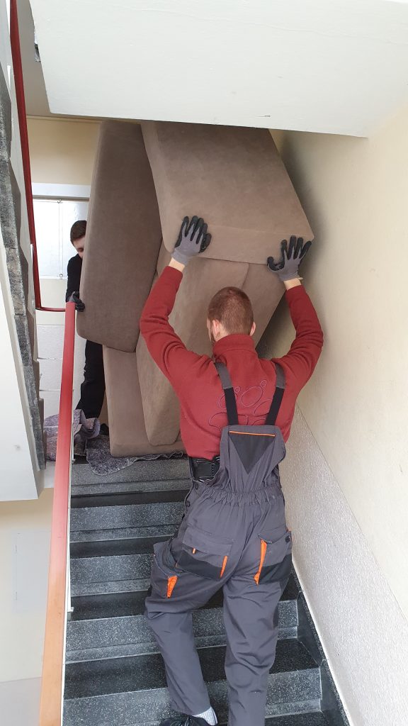 Mitarbeiter von Seniorenumzüge Lüneburg tragen ein Sofa durch ein Treppenhaus