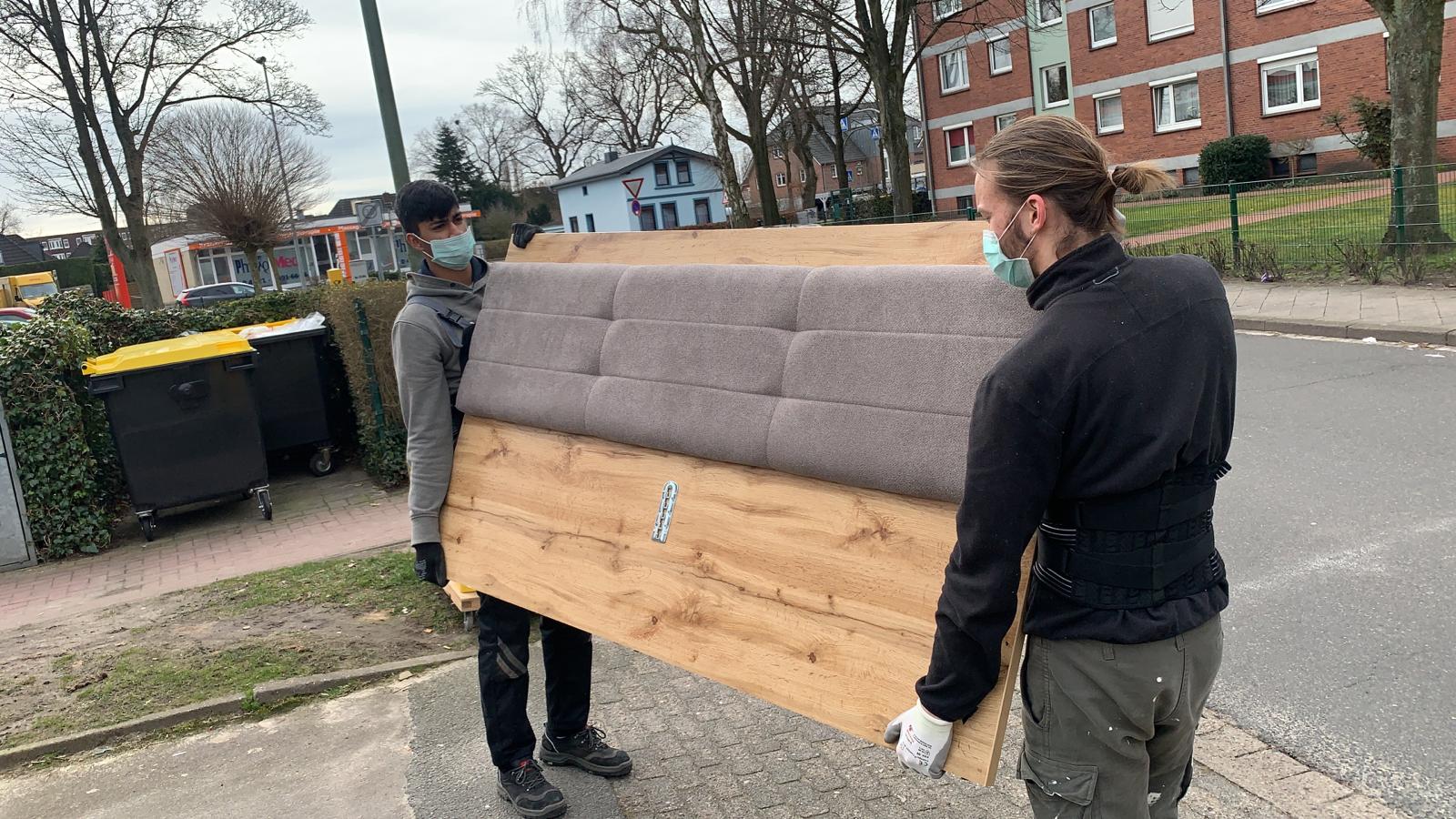 Umzugshelfer von Seniorenumzüge Lüneburg tragen Teile eines Bettes